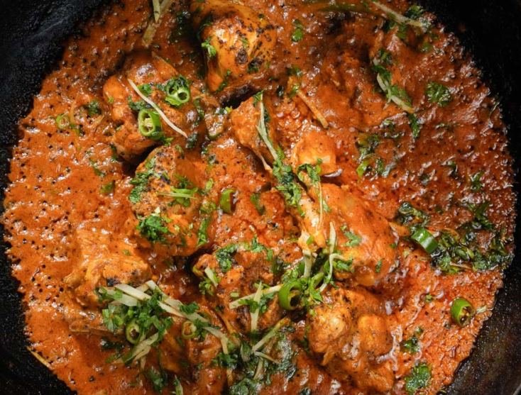 A Monal chicken karahi garnished with fresh ginger